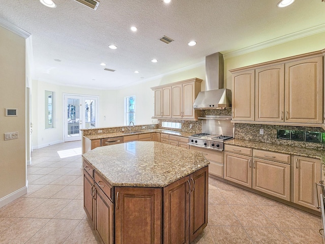 kitchen featuring light tile patterned flooring, a kitchen island, sink, stainless steel appliances, and wall chimney range hood