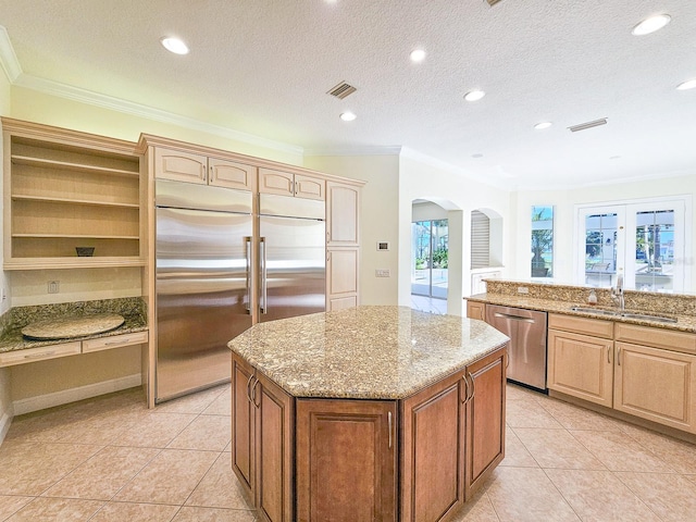 kitchen with appliances with stainless steel finishes, a center island, sink, and light stone countertops