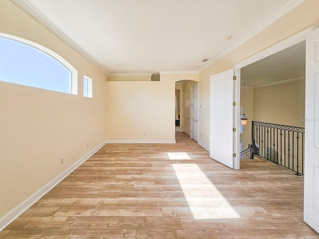 empty room with crown molding and light hardwood / wood-style floors