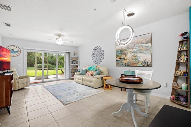 tiled living room with ceiling fan and a textured ceiling