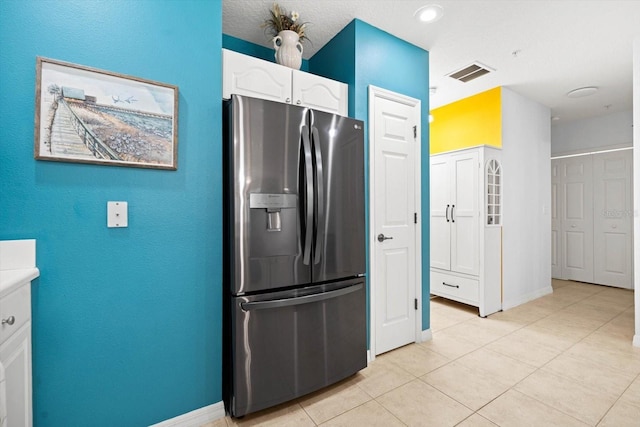 kitchen with stainless steel fridge with ice dispenser, white cabinetry, and light tile patterned flooring