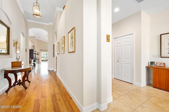 corridor featuring ornamental molding and light hardwood / wood-style flooring