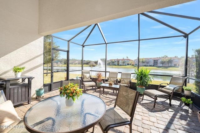 view of patio featuring a lanai, a water view, and an outdoor living space