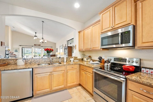 kitchen featuring light stone counters, stainless steel appliances, vaulted ceiling, and sink