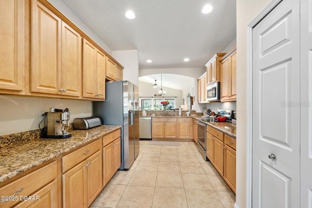 kitchen with light stone countertops, stainless steel appliances, lofted ceiling, light tile patterned flooring, and sink