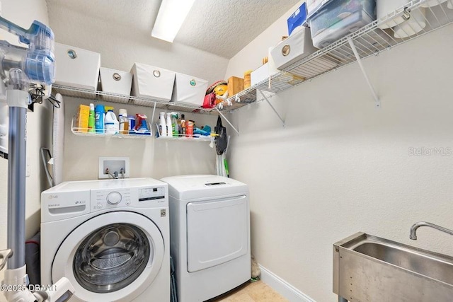 laundry room with sink, washing machine and dryer, and a textured ceiling