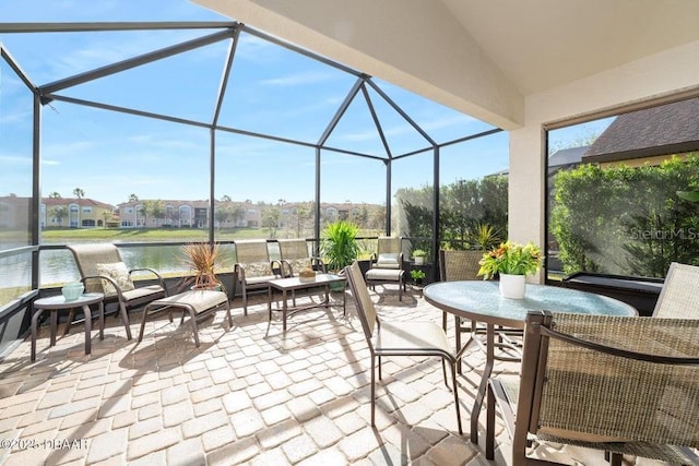 view of patio / terrace featuring a water view, glass enclosure, and an outdoor living space