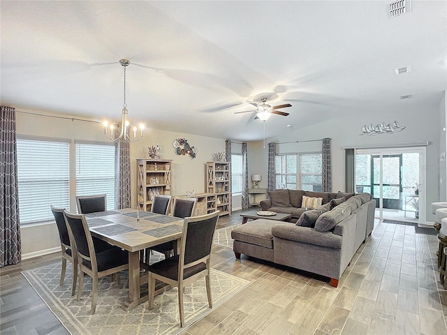 dining room with vaulted ceiling, ceiling fan with notable chandelier, plenty of natural light, and light hardwood / wood-style flooring