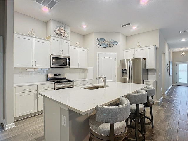 kitchen with sink, white cabinets, a center island with sink, and stainless steel appliances