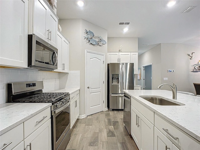 kitchen featuring backsplash, sink, white cabinetry, appliances with stainless steel finishes, and light stone counters