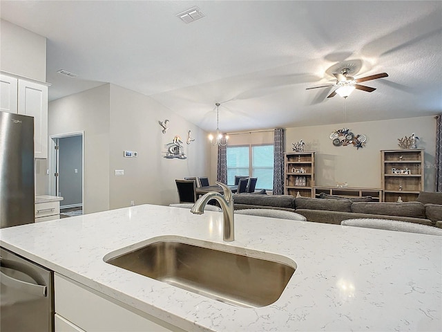 kitchen featuring ceiling fan with notable chandelier, light stone countertops, decorative light fixtures, white cabinetry, and sink