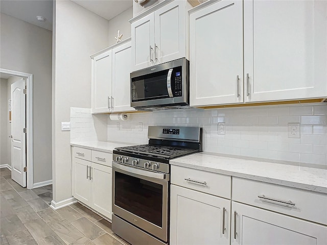 kitchen with light stone counters, white cabinets, backsplash, and appliances with stainless steel finishes