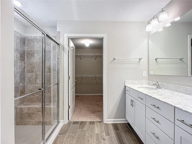 bathroom with a textured ceiling, an enclosed shower, and vanity