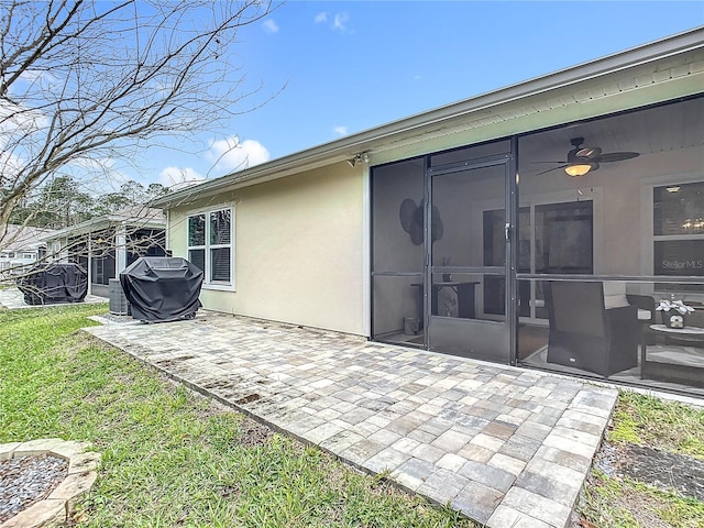 rear view of house with ceiling fan, a sunroom, a lawn, and a patio