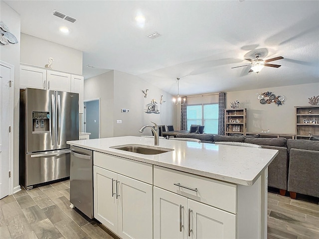 kitchen with an island with sink, sink, stainless steel appliances, and white cabinetry