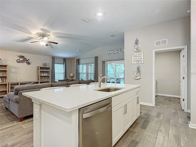 kitchen with a kitchen island with sink, a textured ceiling, stainless steel dishwasher, white cabinets, and sink