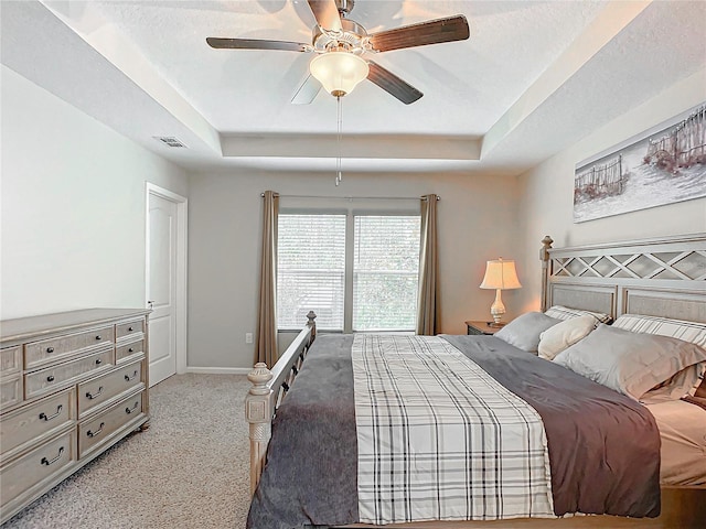 carpeted bedroom with a raised ceiling, ceiling fan, and a textured ceiling