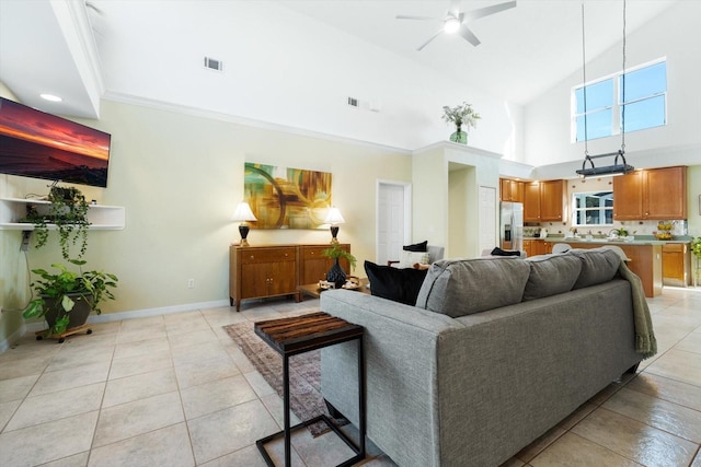 tiled living room with ceiling fan, crown molding, and a towering ceiling