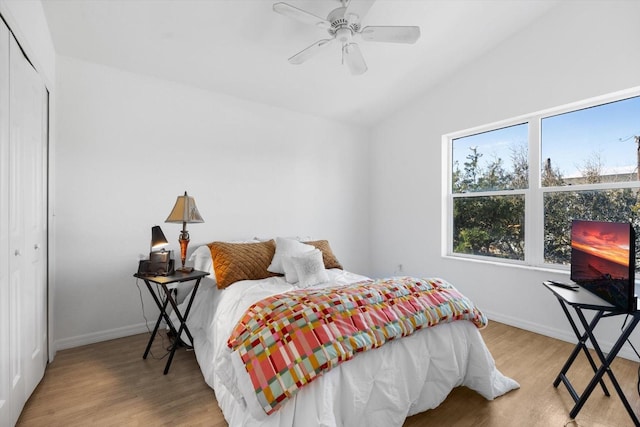 bedroom with ceiling fan, a closet, vaulted ceiling, and light hardwood / wood-style floors