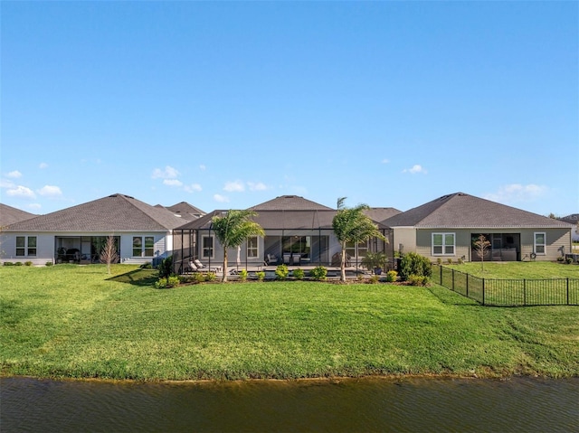 back of property featuring a water view, a lanai, and a lawn