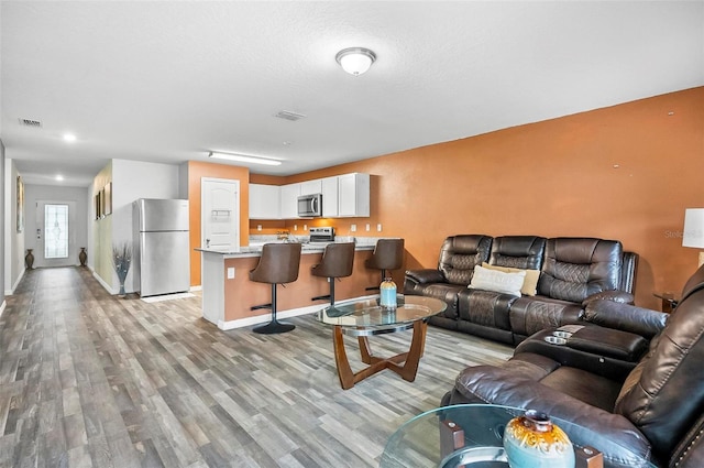 living room with a textured ceiling and light hardwood / wood-style floors