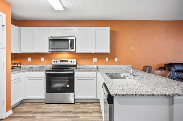 kitchen with kitchen peninsula, stainless steel appliances, white cabinets, and sink