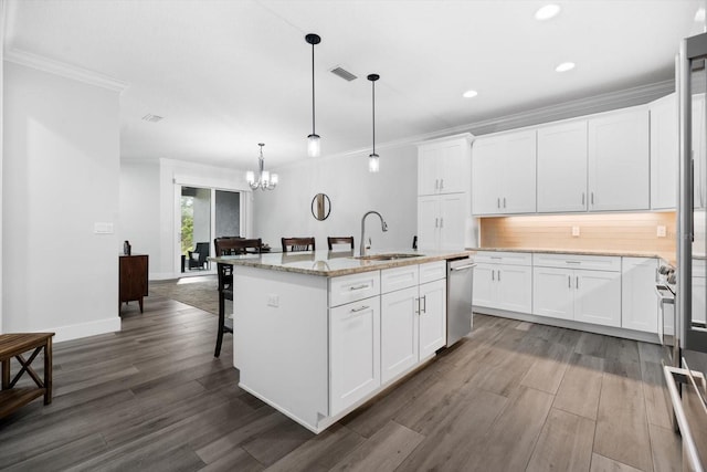 kitchen featuring pendant lighting, sink, white cabinetry, and an island with sink