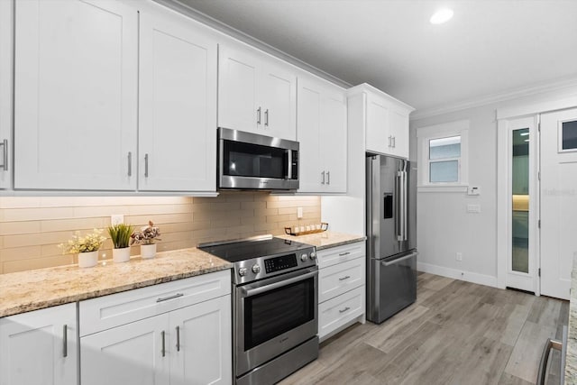 kitchen featuring light stone countertops, tasteful backsplash, ornamental molding, stainless steel appliances, and white cabinets