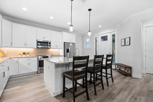 kitchen with white cabinets, a kitchen island with sink, and appliances with stainless steel finishes