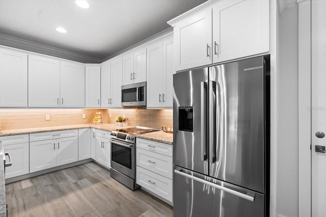 kitchen featuring light stone countertops, backsplash, stainless steel appliances, and white cabinetry