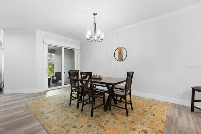 dining area with ornamental molding, light hardwood / wood-style floors, and an inviting chandelier