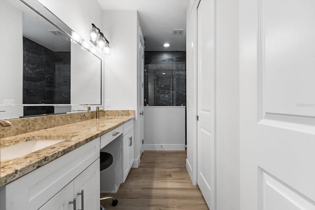 bathroom featuring hardwood / wood-style floors, vanity, and a tile shower