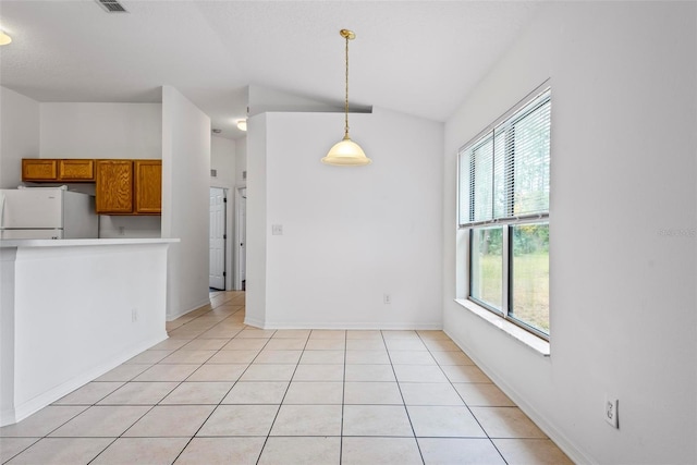 unfurnished dining area featuring light tile patterned flooring and vaulted ceiling