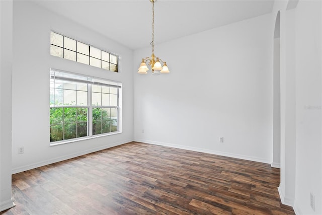 unfurnished room featuring dark wood-type flooring and a notable chandelier