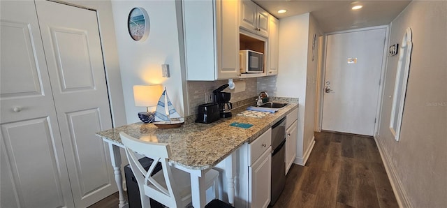 kitchen featuring sink, a kitchen bar, white cabinetry, and backsplash