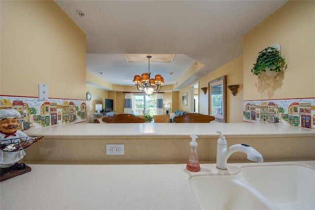 kitchen with sink, decorative light fixtures, an inviting chandelier, and kitchen peninsula