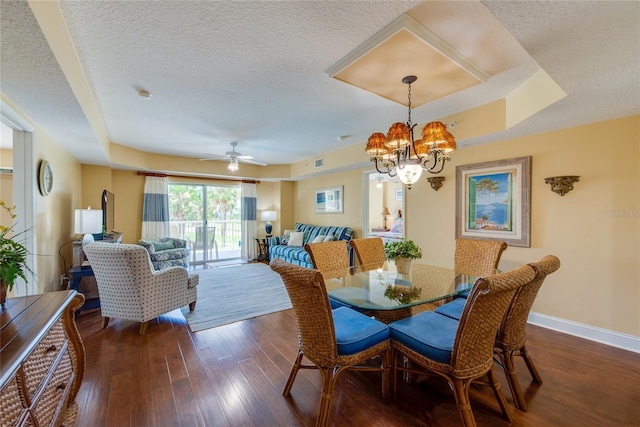 dining area featuring a textured ceiling, dark hardwood / wood-style flooring, ceiling fan with notable chandelier, and a tray ceiling