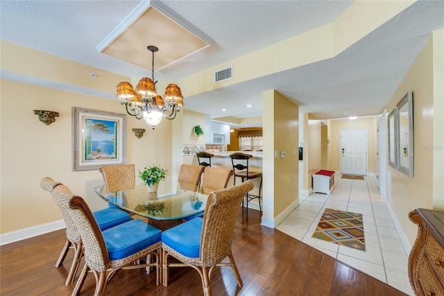 dining area featuring an inviting chandelier, light wood-type flooring, and a textured ceiling