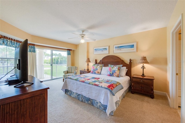 bedroom featuring access to outside, light colored carpet, ceiling fan, and a textured ceiling