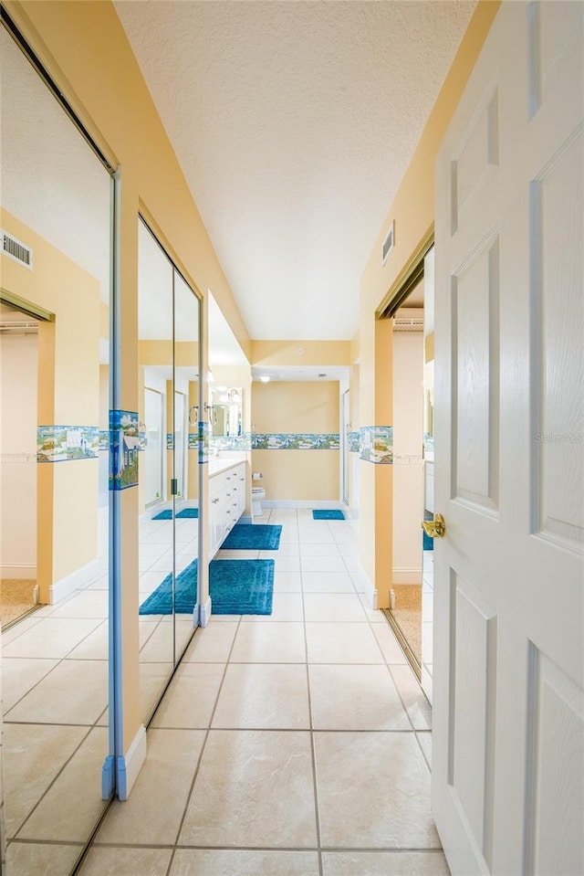 hallway featuring light tile patterned flooring and a textured ceiling