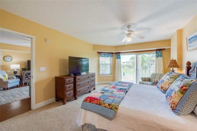 carpeted bedroom featuring ceiling fan, access to outside, and a textured ceiling