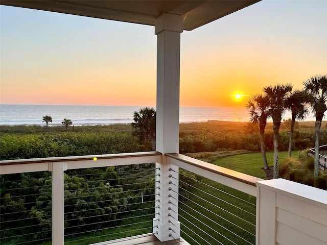 balcony at dusk featuring a water view