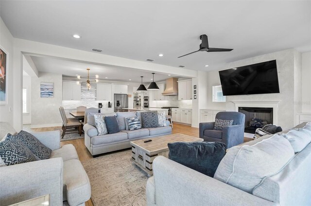 living room with ceiling fan and light wood-type flooring