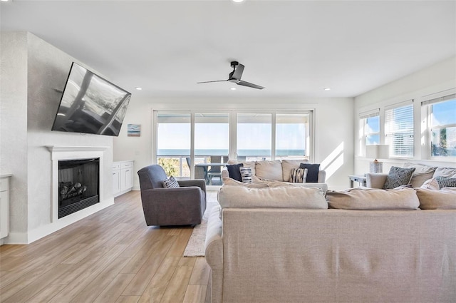 living room featuring ceiling fan, a healthy amount of sunlight, and light wood-type flooring