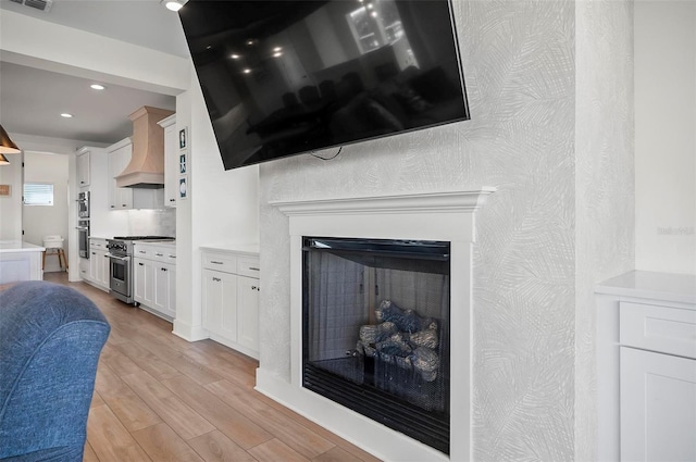 room details with stainless steel appliances, hardwood / wood-style floors, and custom exhaust hood