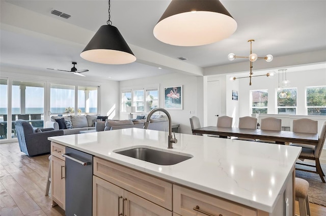 kitchen with sink, a water view, dishwasher, an island with sink, and pendant lighting