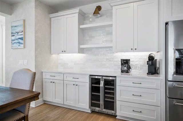 kitchen with white cabinetry, tasteful backsplash, stainless steel fridge with ice dispenser, beverage cooler, and light wood-type flooring