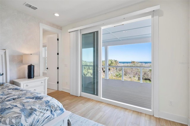 bedroom featuring light hardwood / wood-style flooring, access to outside, and a water view