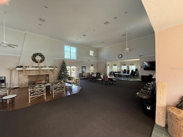 exercise room with ceiling fan, a fireplace, and a towering ceiling