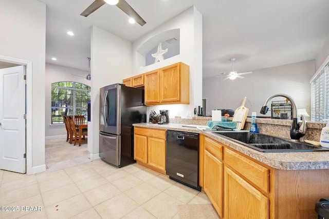 kitchen featuring sink, black dishwasher, ceiling fan, light tile patterned floors, and stainless steel refrigerator